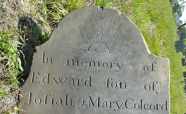 Edward Colcord's chipped slate gravestone laying on the grass