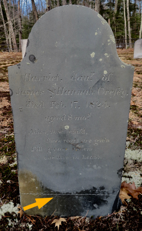 slate gravestone set upright in the ground, an arrow added to accent the staining on the bottom width and where the burial line is carved on it