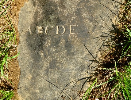 slate fragment showing the letters A B C D E carved into the stone