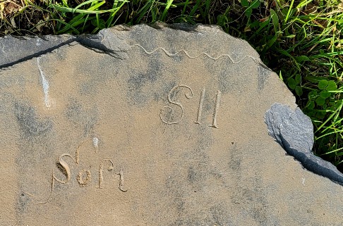 slate fragment with letters $11 and baseline carved into it