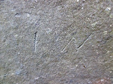 magnified detail of initials scratched into a slate stone