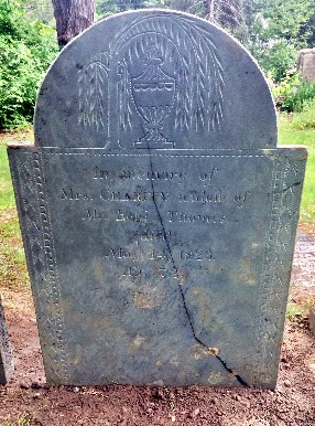 Slate gravestone carved with an urn and willow, fancy borders, and an inscription. A large crack spans from the bottom right corner up through the top middle of the stone.