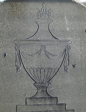 carving detail of an urn with bunting and a flame from an old slate gravemarker