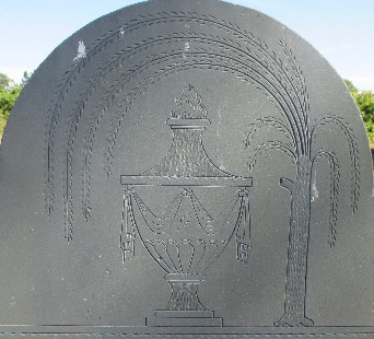 detail from an old slate gravestone for Lydia Carver carved with an urn and a willow